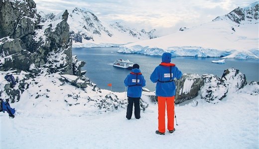 Zwei Reisende wandern in der Antarktis bei einem Ausflug zurück durch den Schnee.