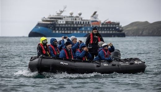 Antarktis Reisende sitzen auf Zodiac und im Hintergrund steht das Expeditionsschiff.