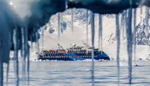 Durch einen Eisvorhang sieht man das Antarktis Schiff von Albatros Expeditions.