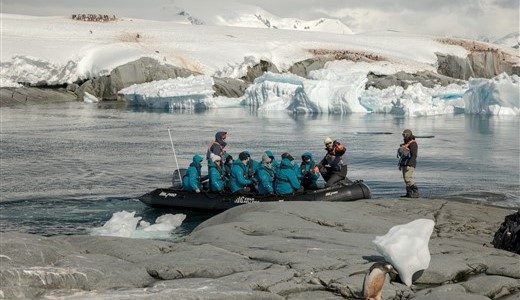 Zodiac landet auf der Antarktis Reise mit Gästen an einem Felsen an